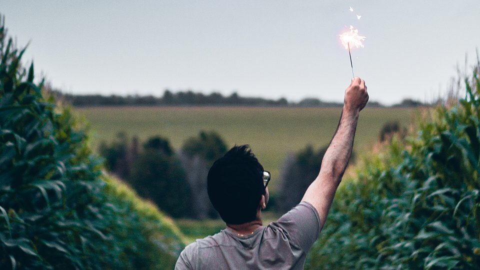 man holding a sparkler in a field