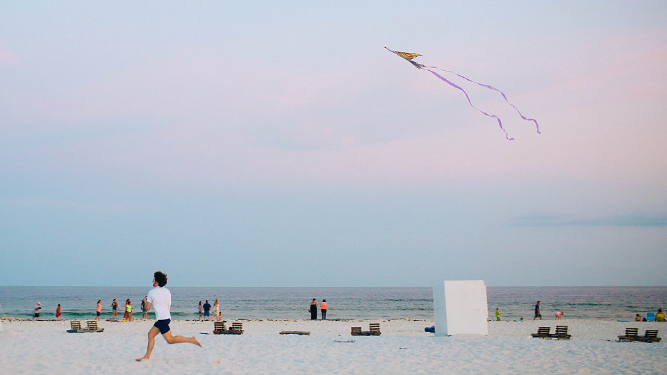 man running with kite on the beach