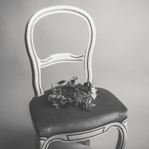 An empty chair with a flower crown sitting on it