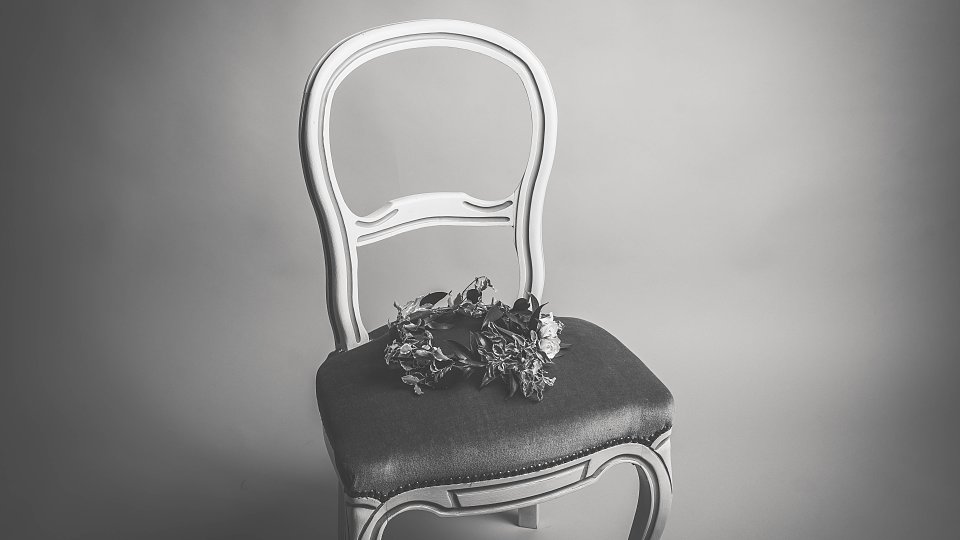 An empty chair with a flower crown sitting on it
