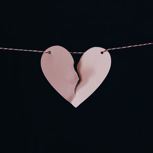 light pink paper heart ripped down the middle and held together by a string