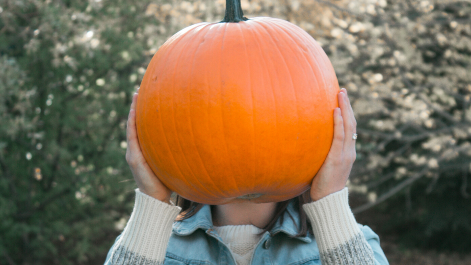 girl holding big pumpkin in front of face
