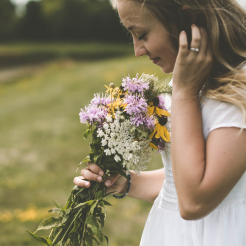 girl smelling wild flowers in a field