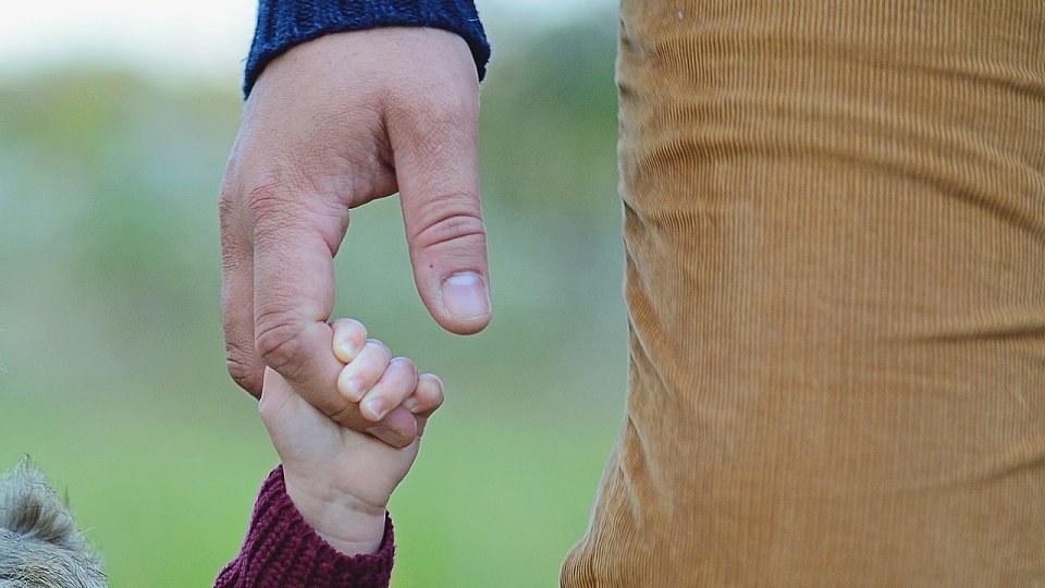 little girl gripping father's finger