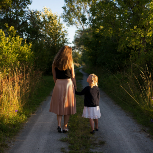 mother and daughter walking down a dirt road together
