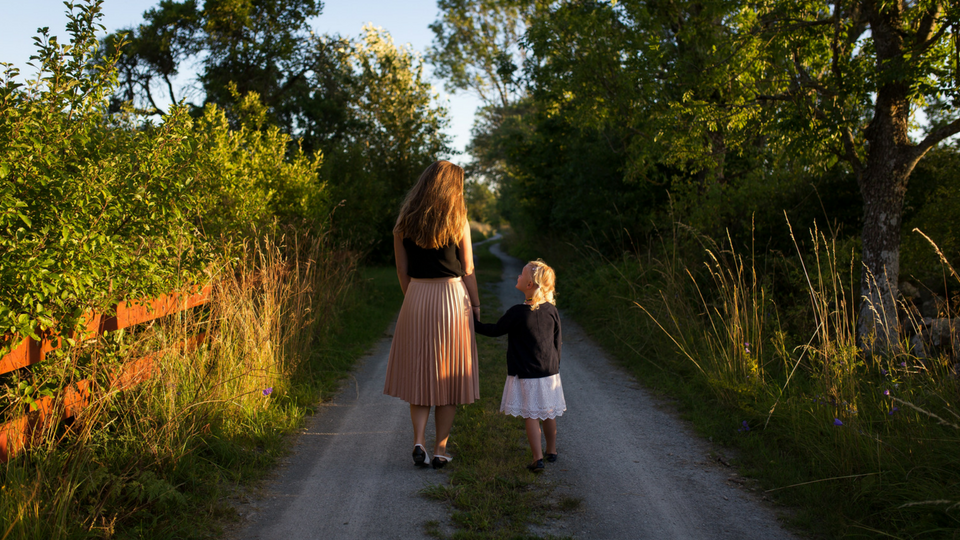 mother and daughter walking down a dirt road together