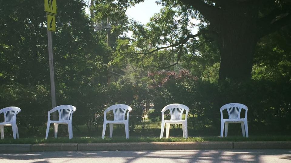 white plastic chairs lined up on the side of the road