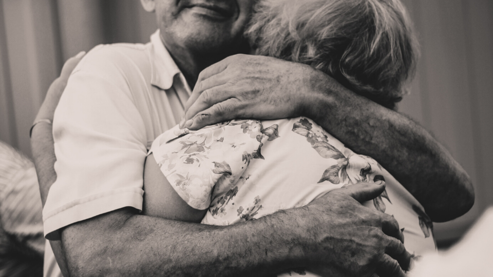 black and white picture of an elderly man and woman hugging