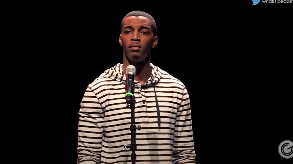 Joseph Soloman standing in front of a black backdrop wearing a white sweatshirt with black stripes