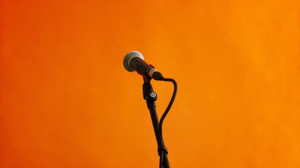 Orange backdrop with a black microphone stand in front of it