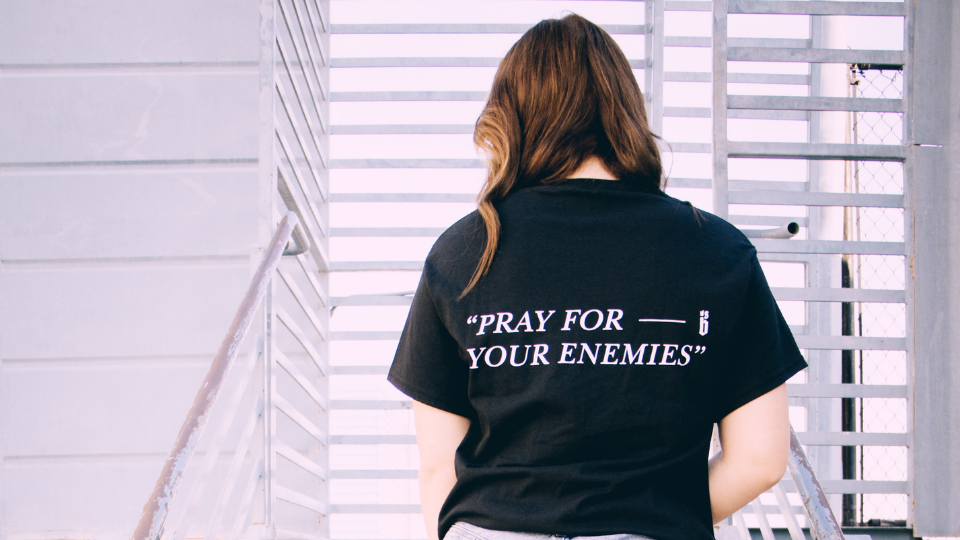 black shirt that says pray for your enemies
