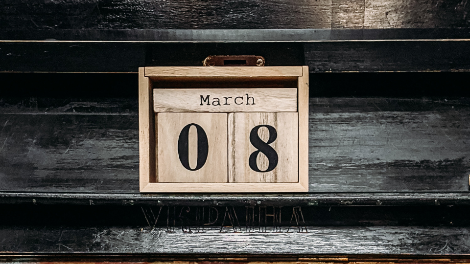 old wooden black piano with a wooden block calendar that reads March 08 sitting on top of piano