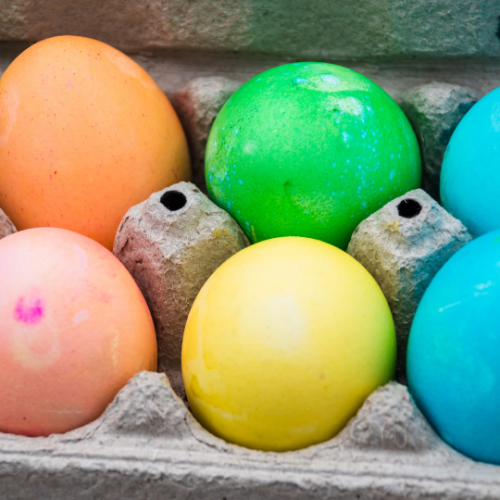 eggs dyed rainbow colors sitting in a brown egg carton