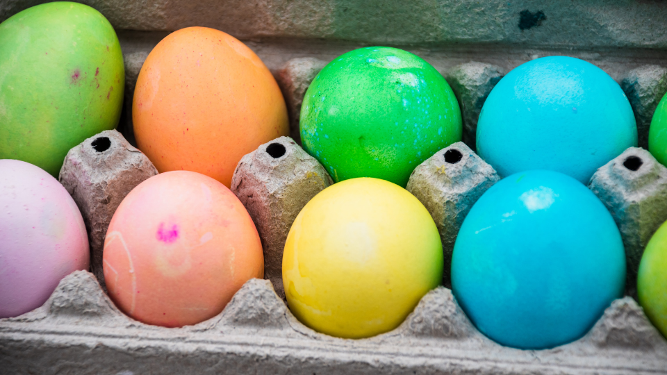 eggs dyed rainbow colors sitting in a brown egg carton