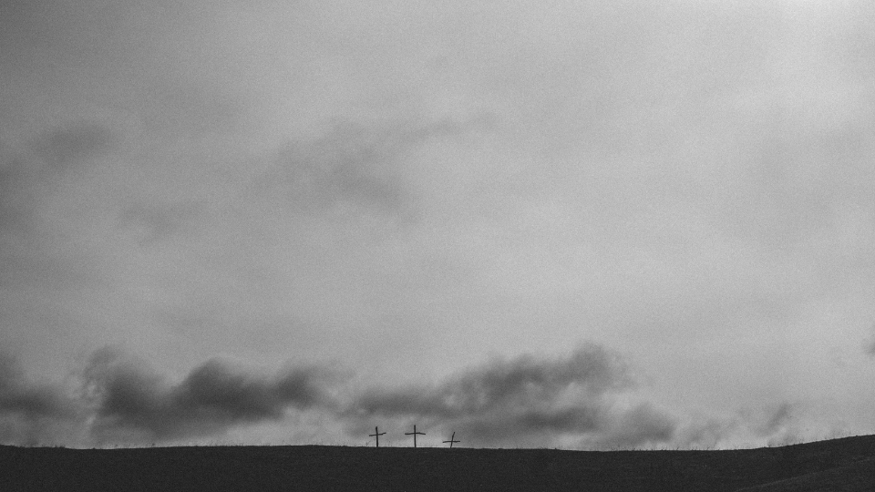 grey sky with three crosses sitting on a hill in the distance