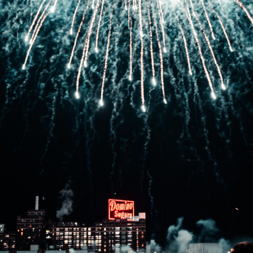 bright white fireworks showering down over the red domino sugar neon sign in Baltimore Maryland