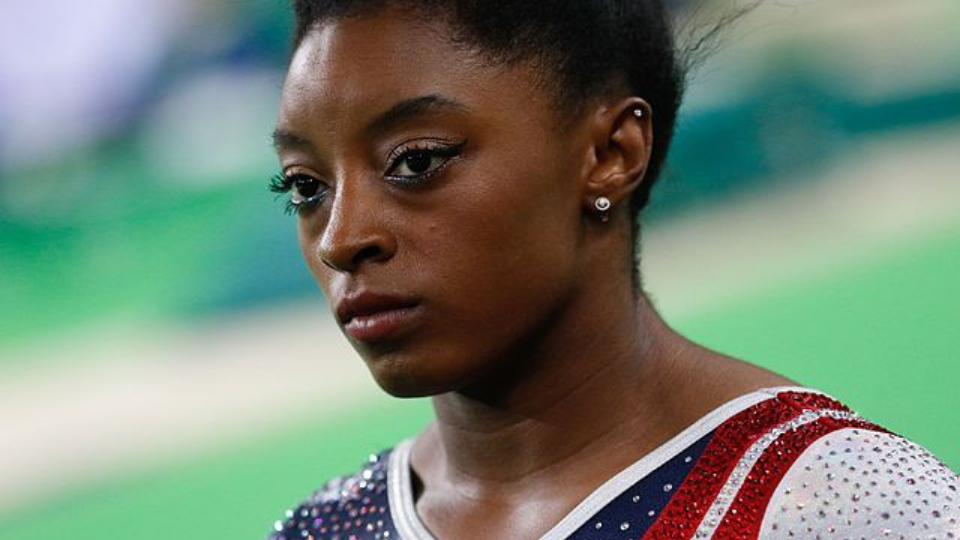 close up of Simone Biles wearing a red white and blue bedazzled gymnastics uniform staring straight ahead at the 2016 Rio Olympics
