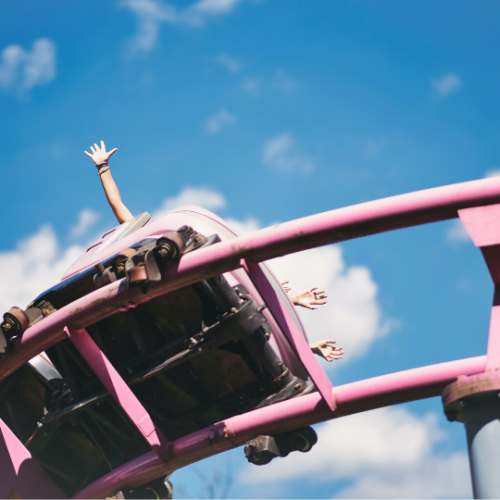 picture taken from below of pink rollercoaster tracks