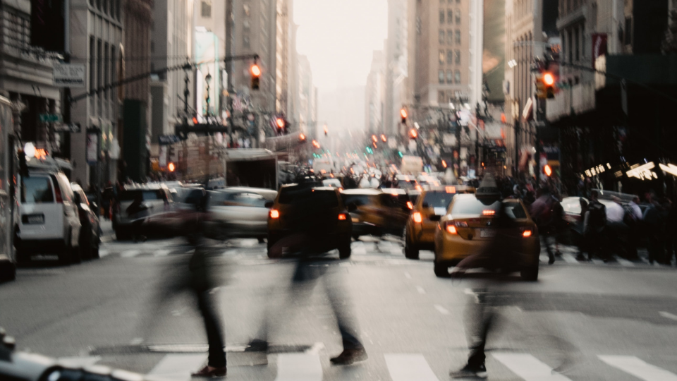 blurs of people crossing a crosswalk in busy street of New York City