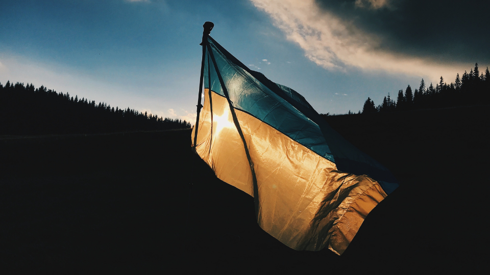 Ukrainian flag blue and yellow flying with the sun shining through it