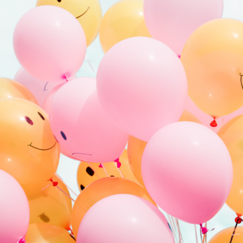 Group of pink and yellow ballons with smiley faces on tham