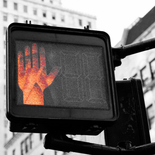 red hand lit up on a street sign to signal for pedestrians to stop walking