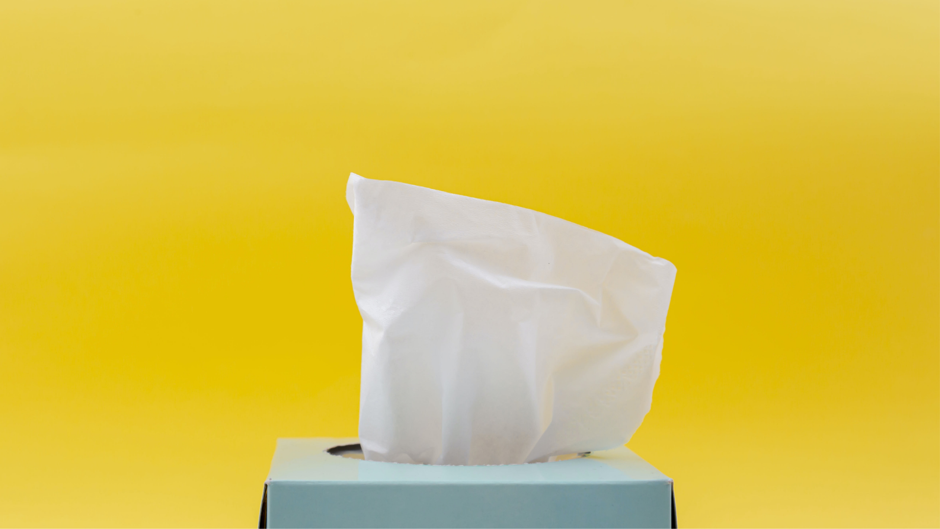 pale blue tissue box sitting in front of a yellow background