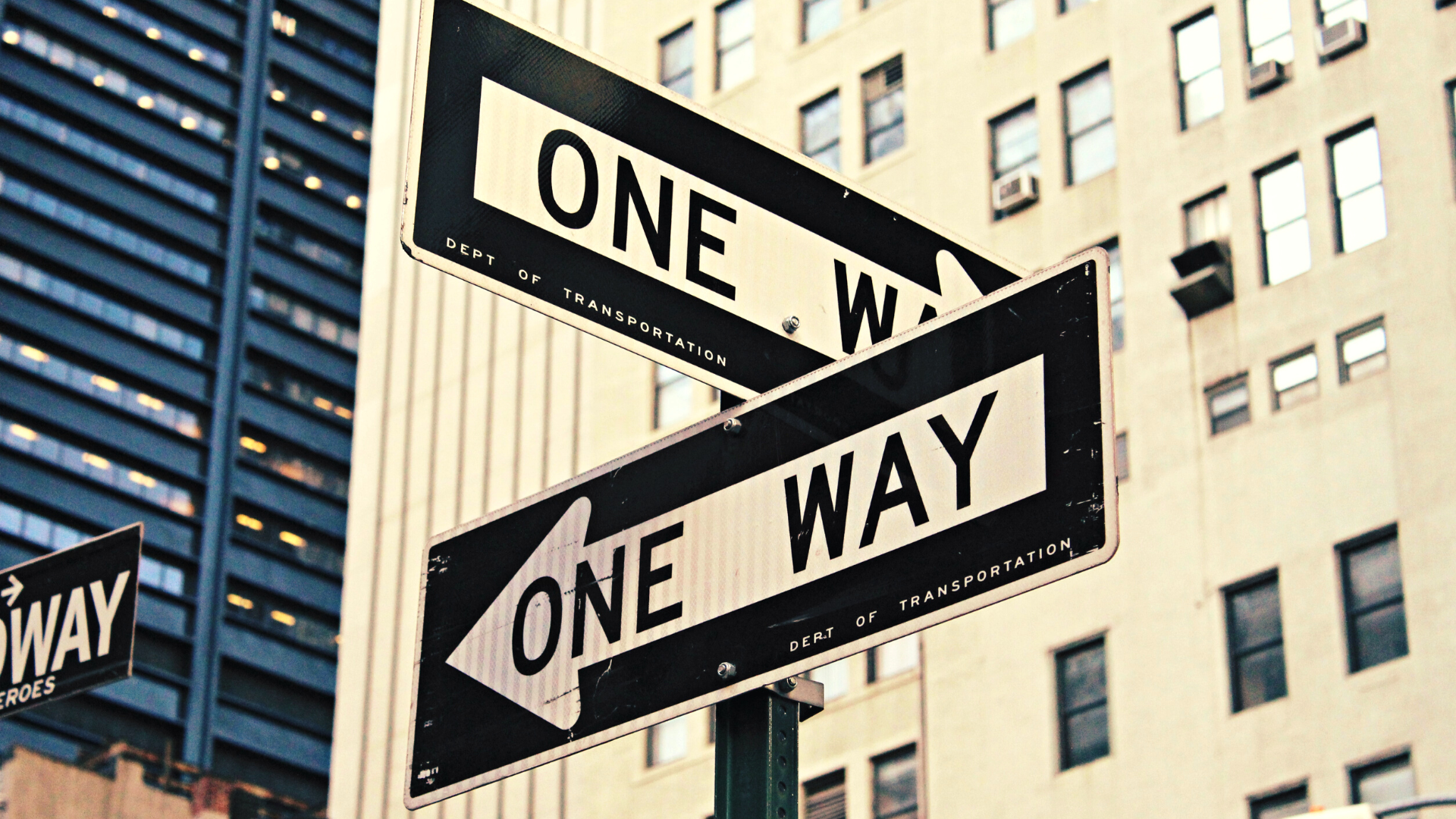 two street signs that read One Way pointing different directions