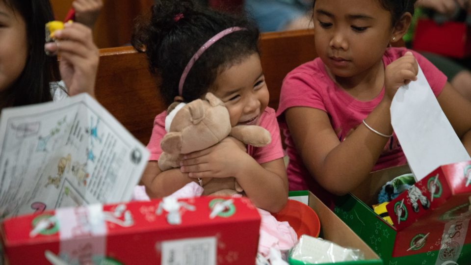 A girl in Saipan tenderly hugs the teddy bear she found in her shoebox gift.