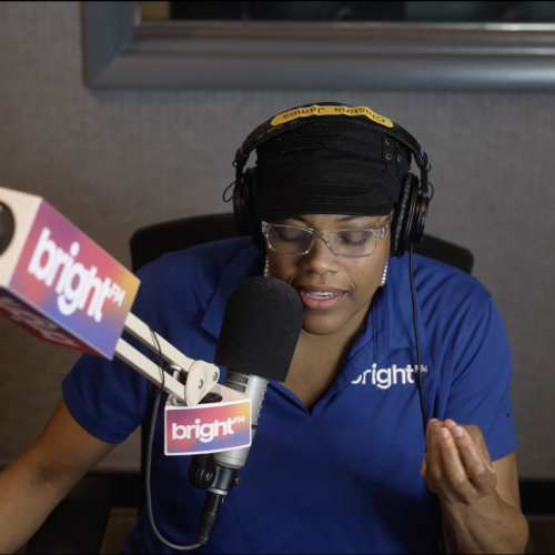 Middays DJ, Christina James, pictured sitting in the BRIGHT-FM studio and speaking into a radio microphone