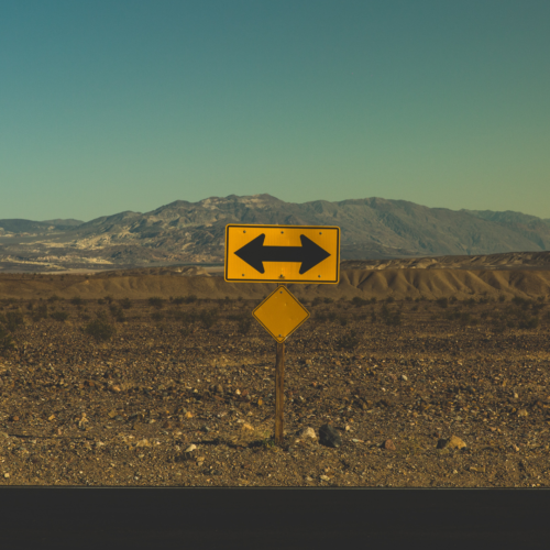 yellow two-way turn sign at the end of a road in a desert