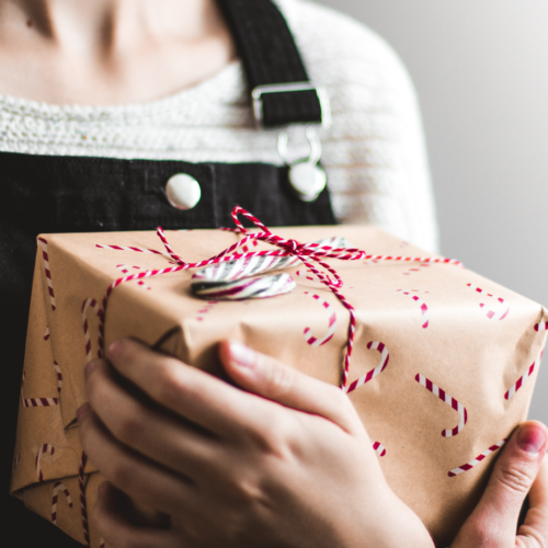 girl holding a gift wrapped in brown paper tied with a red ribbon