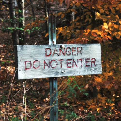 wooden sign in front of trees reading DANGER DO NOT ENTER