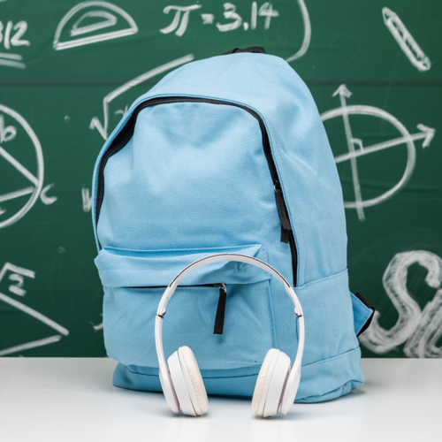 Blue backpack with white headphones in front against a chalkboard