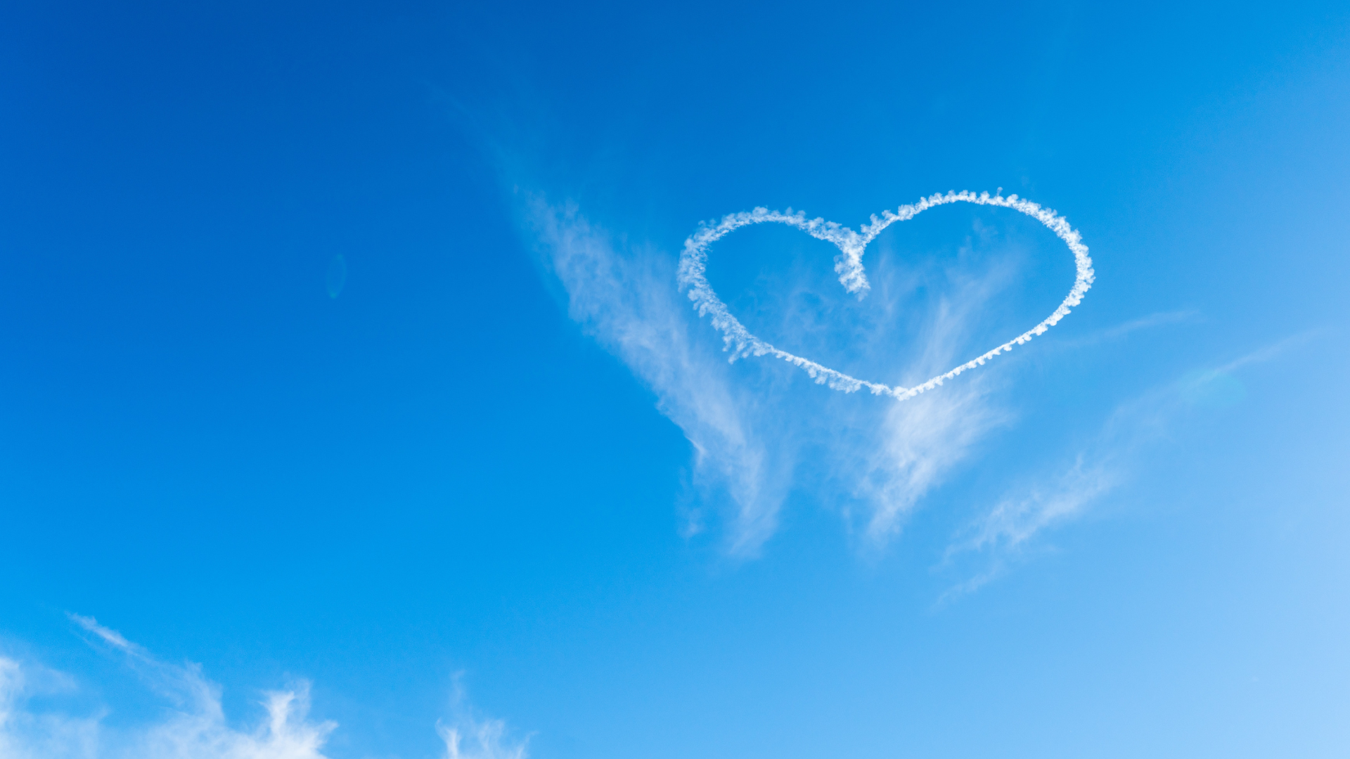 a blue sky with a white heart in it that was drawn by a plane